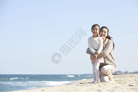 海边沙摊上母女抱在一起背景图片