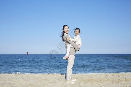 海边沙滩上在妈妈背上的女孩图片