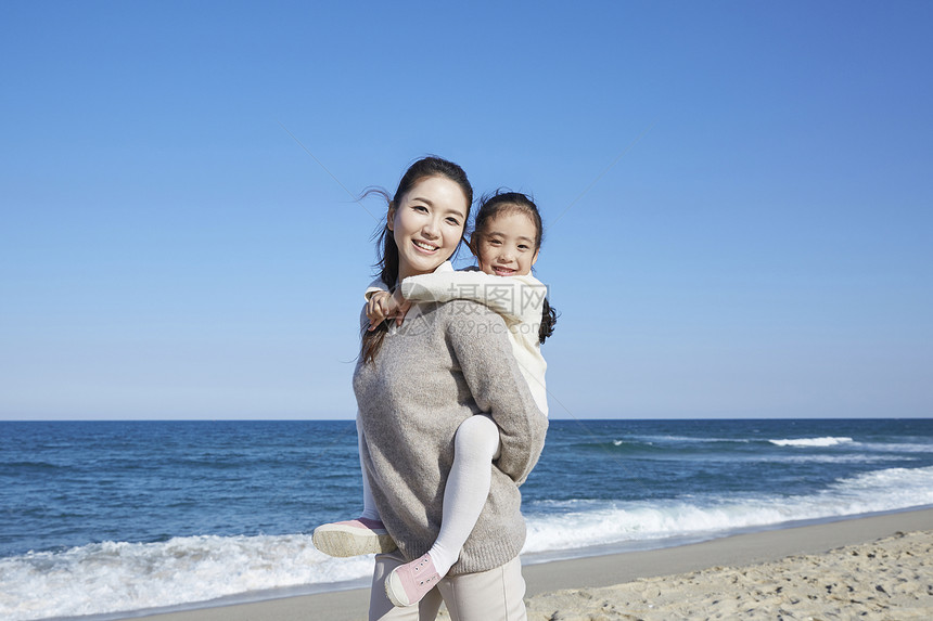 海边沙滩上的母亲背着女儿图片