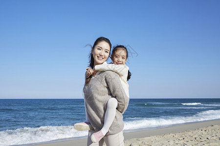 海边沙滩上的母亲背着女儿图片