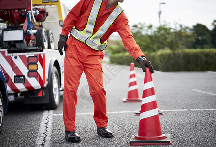 锥形交通路标搬运桶锥放置路障的道路救援服务人员背景