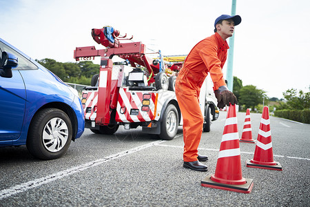 锥形交通路标放置路障锥桶的道路救援服务人员背景