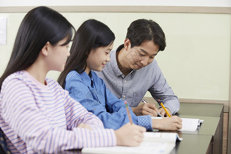 老师在教室里指导学生写作业图片