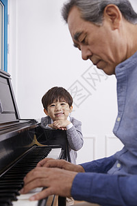 男孩看着爷爷弹奏钢琴图片