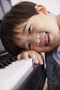 男孩趴在钢琴上嬉笑图片