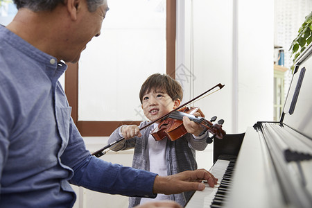 拉小提琴男孩祖父孙子在一起弹钢琴拉小提琴背景