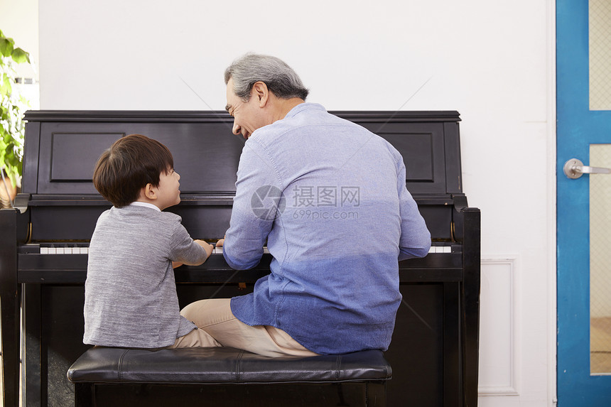快乐祖父孙子一起弹钢琴背影图片