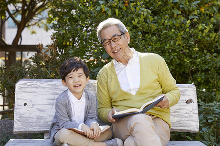 男孩坐在阳台上坐在长凳上看书的祖孙背景