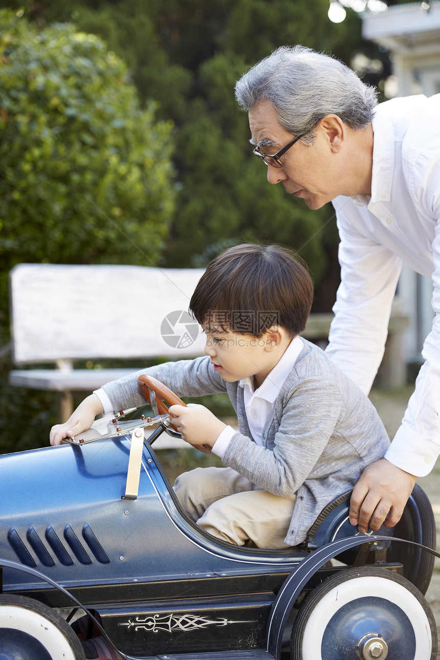 祖父陪孙子玩微型汽车玩具图片
