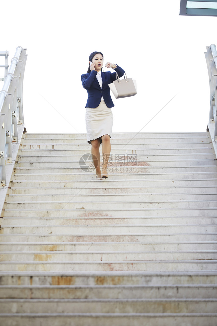 接着电话走下楼梯的年轻女性图片