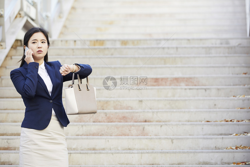 打电话看着手表担心的女青年图片