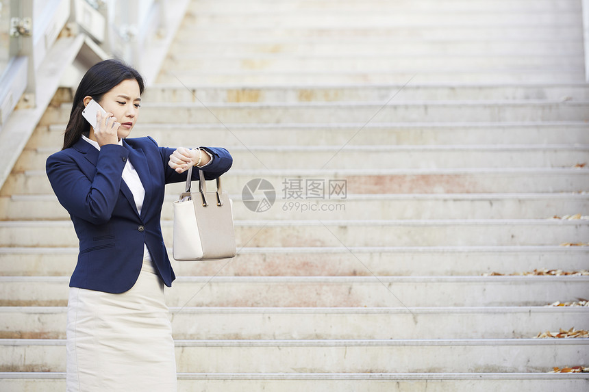 看着时间打电话担心的年轻女子图片