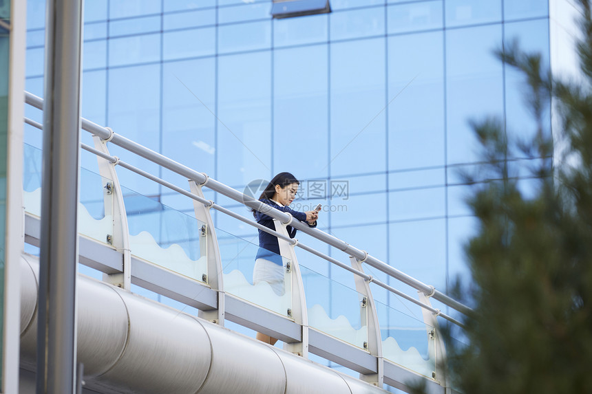 靠栏杆上玩手机的女青年图片