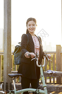 夕阳下推着自行车微笑的年轻女子图片
