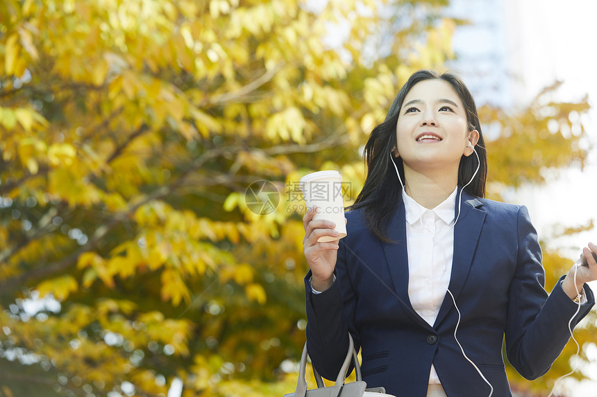 拿着咖啡戴着耳机的年轻女性图片