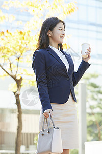 穿着职业套装拿着咖啡的女青年图片