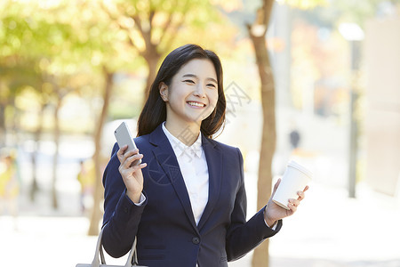 拿着手机和咖啡微笑的女青年图片