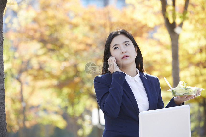 户外拿着沙拉打电话的职业女性图片