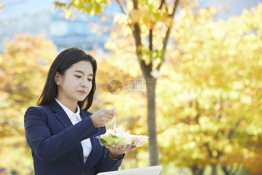 户外吃着沙拉的女青年图片