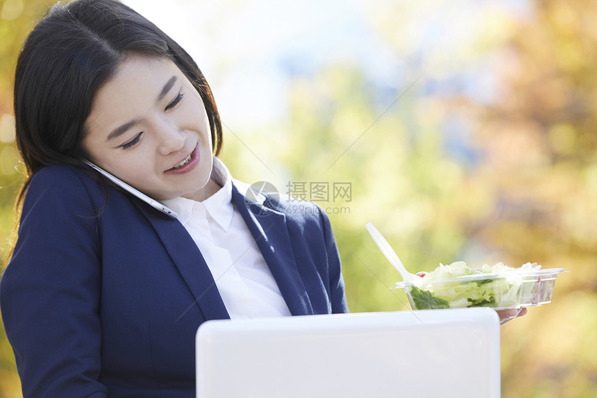 拿着沙拉接电话忙碌的职业女性图片