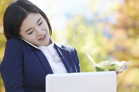 拿着沙拉接电话忙碌的职业女性图片