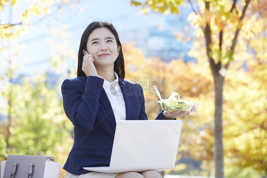 公园里打电话微笑的女青年图片