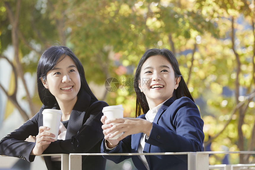 靠在栏杆上喝咖啡放松的成年女性图片