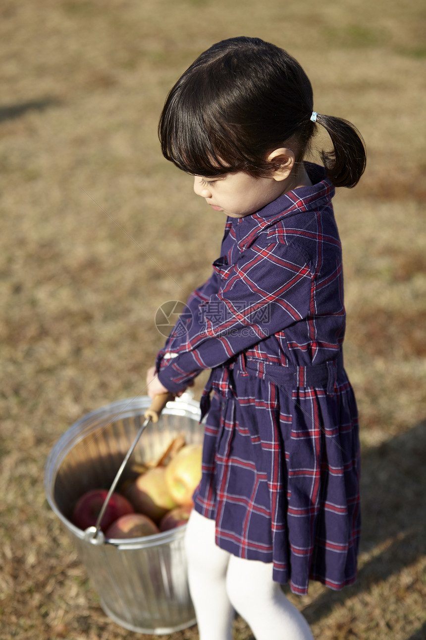 草地上的小女孩拎着水桶图片