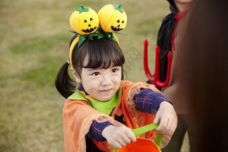 户外草地上万圣节装扮的小女孩开心玩耍图片