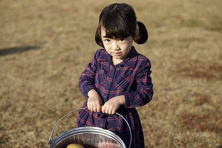 小女孩在户外草地上拎着水桶图片
