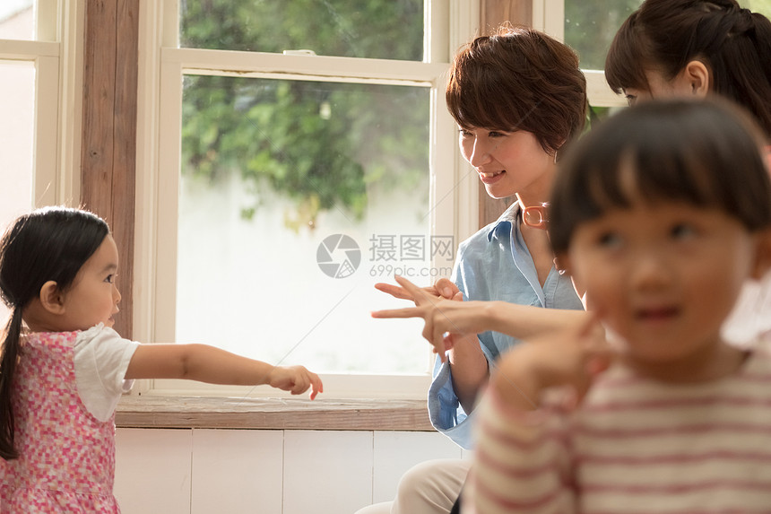 演奏年轻的女孩茶父母在客厅里放松图片