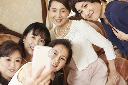 房屋坐着主妇妇女用智能手机拍摄图片