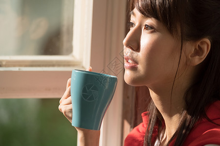 站在窗户旁喝水的女孩图片