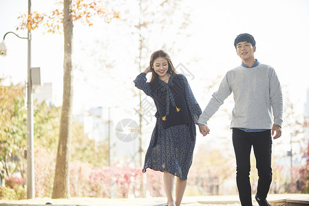 秋天公园里手牵手散步的情侣图片