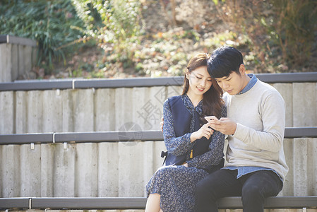 坐在台阶上看手机的情侣背景图片
