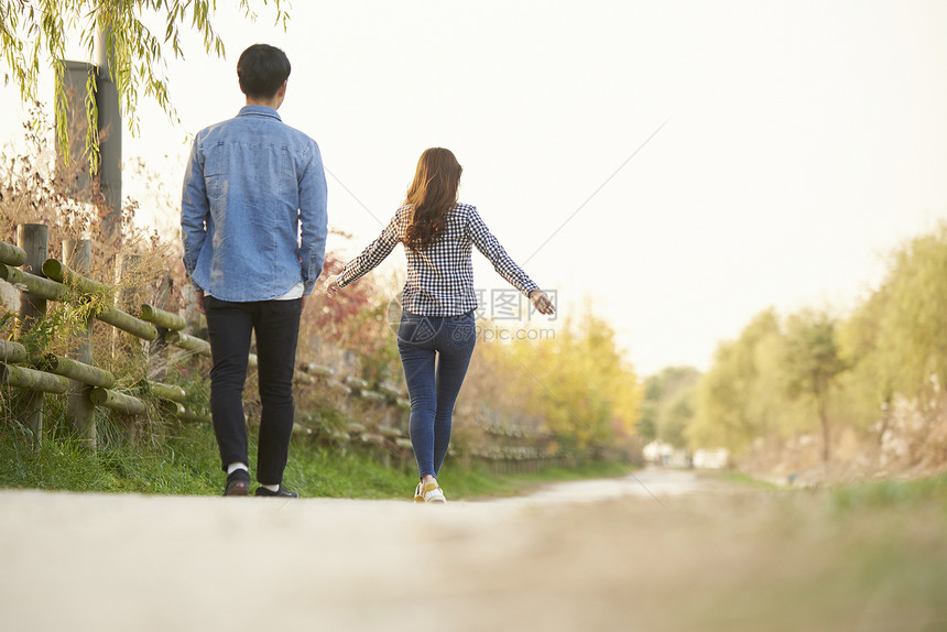 秋日公园里散步的情侣背影图片