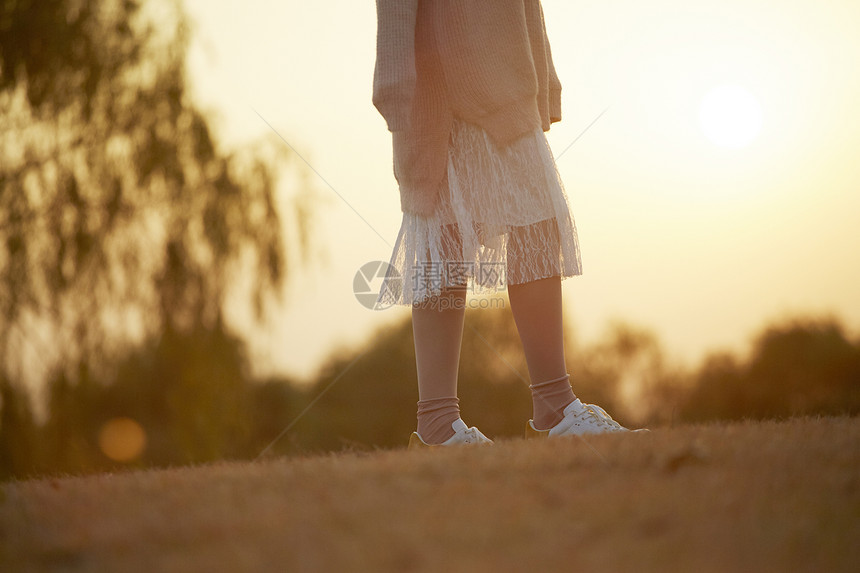 落日公园草坪上的年轻女子图片