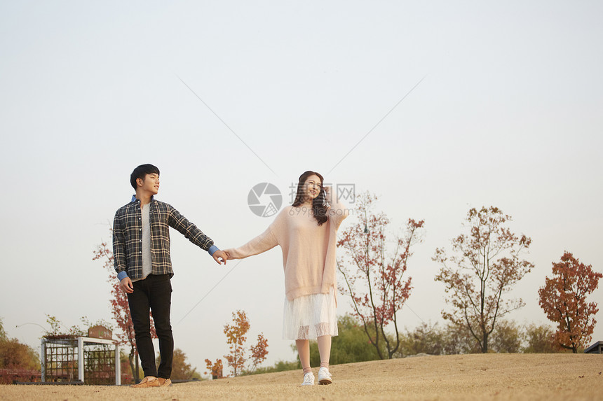 公园里手牵手约会的情侣图片