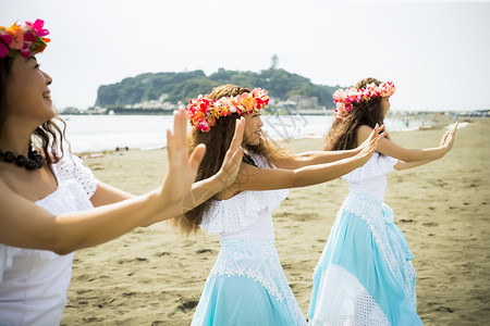 二十几岁戏服有趣跳舞在海滩的hula舞蹈家图片