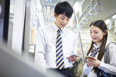 男女学生地铁上玩手机交流图片