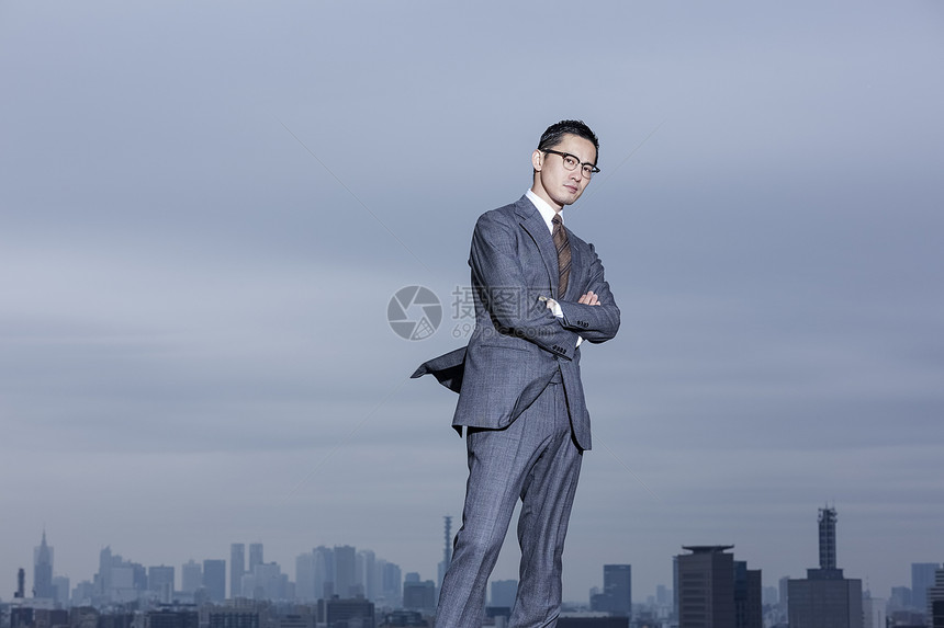 男子注视镜头双臂交叉站立在屋顶的商人图片