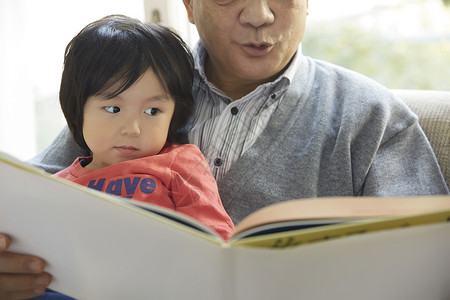 微笑的爷爷和孙子一起玩看书图片