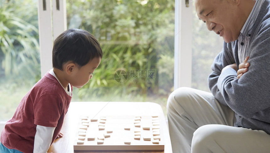 微笑的爷爷和孙子一起玩将棋图片