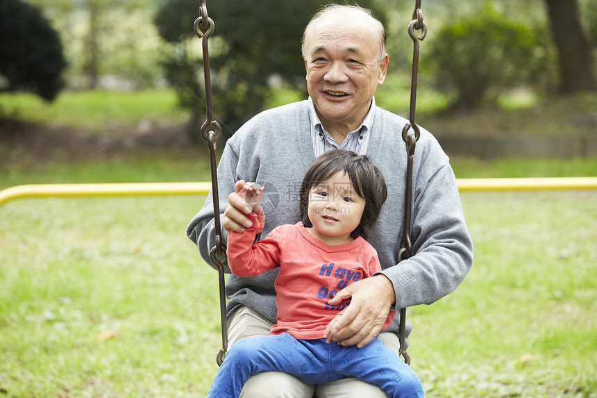 微笑的爷爷和孙子一起荡秋千图片
