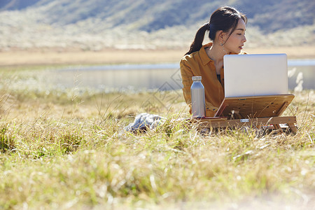 外出手提电脑孤旅在草地上工作的女人图片