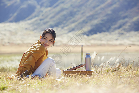 坐着在草地上工作的女人图片