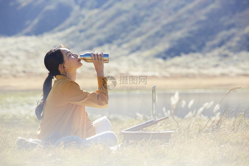 在草地上工作的女人喝水图片