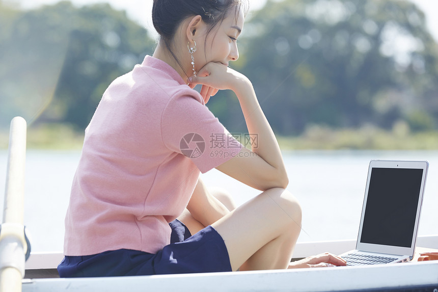 湖泊船上的年轻女孩用笔记本电脑图片