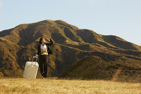 女乘务员草原上的带着行李箱的酷女孩背景