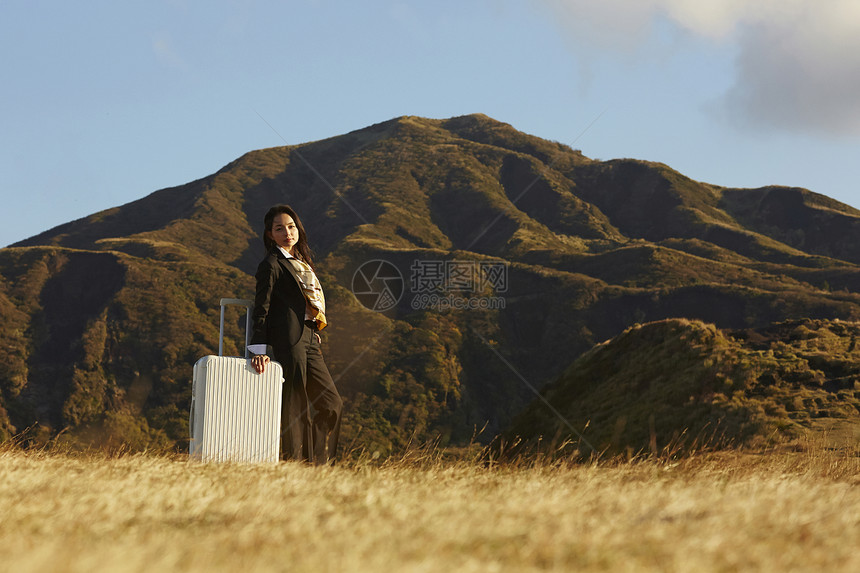 草原上的带着行李箱的女商人图片
